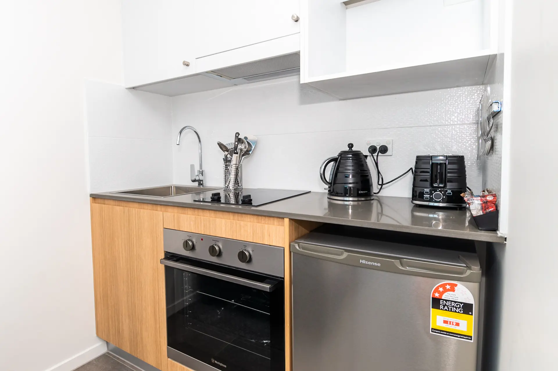 Compact kitchenette with electric cooktop, oven, kettle, toaster and bar fridge