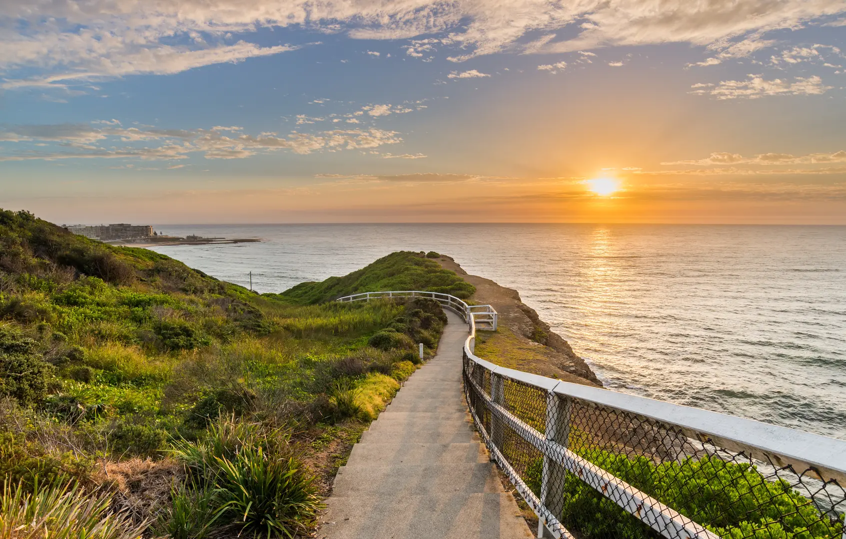 A coastal boardwalk at sunrise above Newcastle ocean baths, the kind of walk that becomes routine when you live nearby